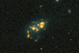 A dwarf galaxy, some 48 million light years away. The orange blobs are hydrogen 