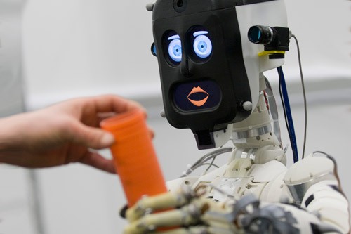 BERT2, a humanoid robot assistant, hands something to a human