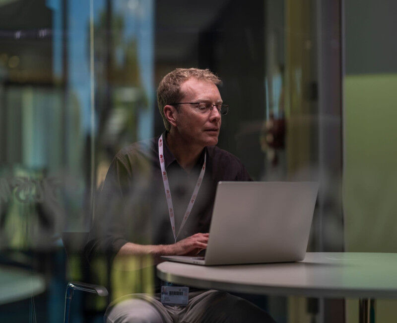 ANU expert Dan Andrews sitting down with his laptop.