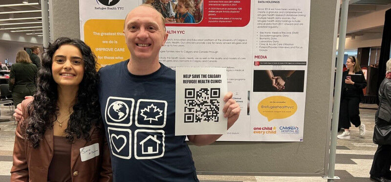 Eric Norrie, right, with colleague Sara Al Sharani staff a Refugee Health YYC bo