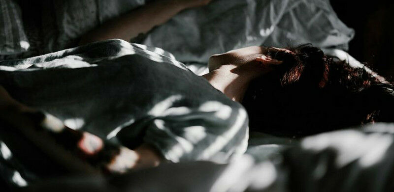 A person laying in a bed under a blanket Credit: Annie Spratt