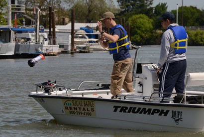 Andrew Tinka tosses a floating robot into the Sacramento River. (Jerome Thai pho