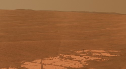 This image shows an outcrop of rocks at the foot of the rover and beyond these r