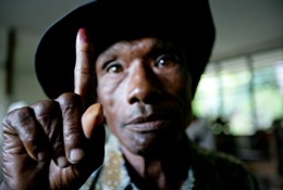A man demonstrates the ink on his finger, confirming his early-morning vote in T