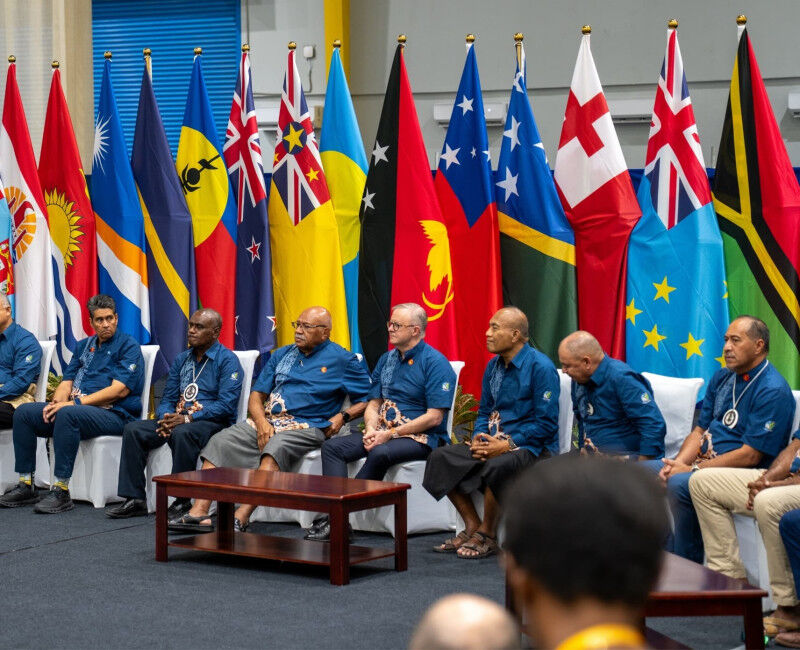 Flags of various Pacific Islands set behind a panel of seated leaders