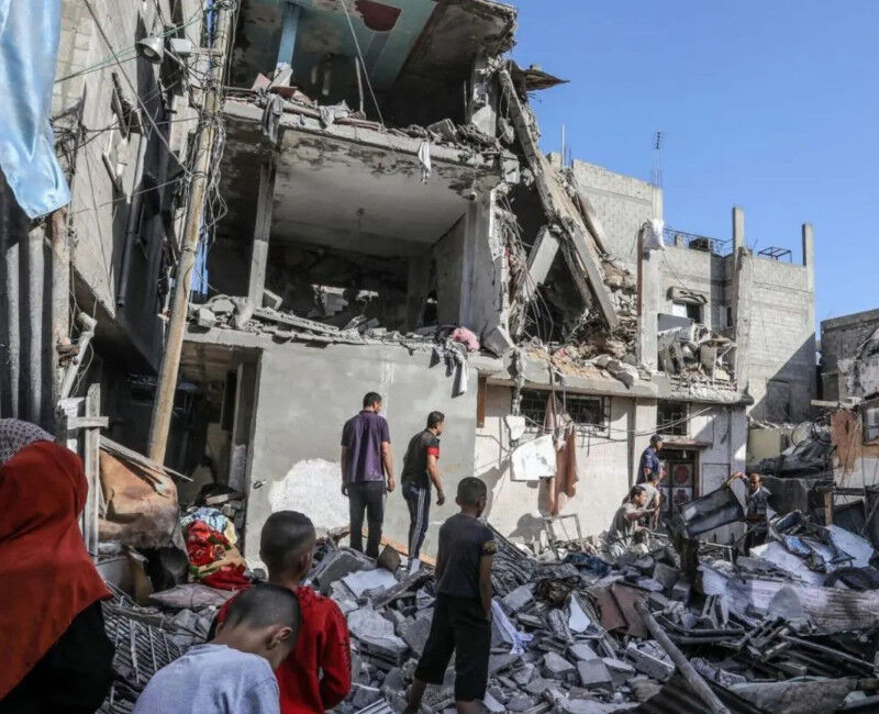 People surround a damanged building in Gaza