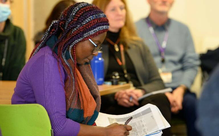A student with colourful plaited hair studying some papers