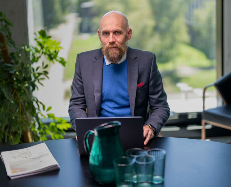Nicholas Biddle sits behind a laptop with report next to him