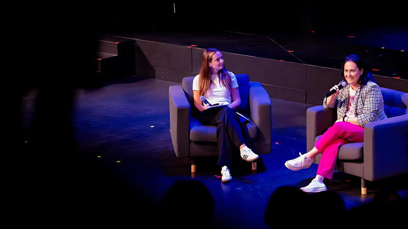 Rachel Bartholomew is interviewed on stage, seated with an interviewer under the